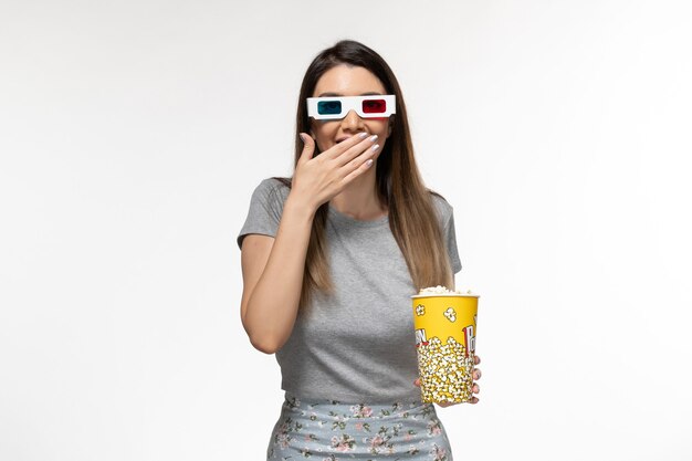 Front view young female holding popcorn and watching movie in d sunglasses on light-white surface