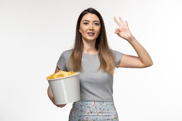 Front view young female holding potato chips while watching movie on white desk