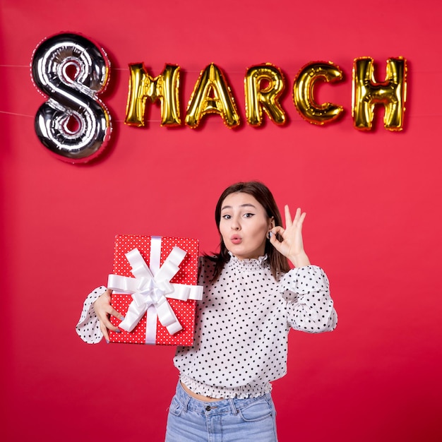 Front view young female holding present on red background woman holiday beauty equality shopping affectionate horizontal feminine march love