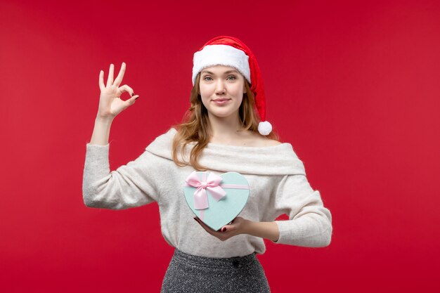 Front view of young female holding present on red floor holiday christmas gift red