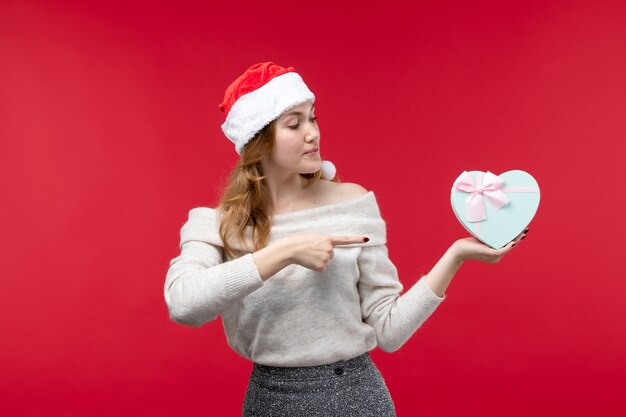 Front view of young female holding present on red floor holiday red christmas gift