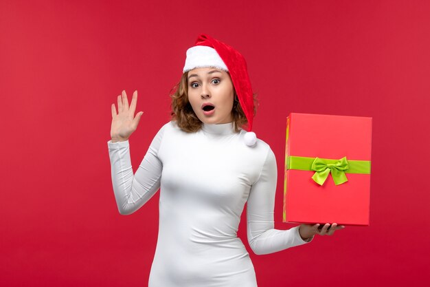 Front view of young female holding present on red