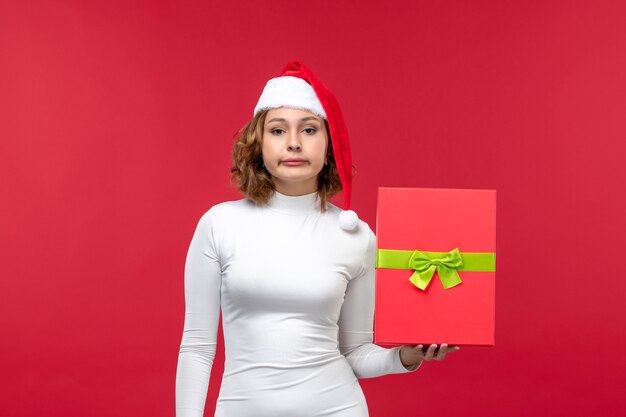 Front view of young female holding present on red