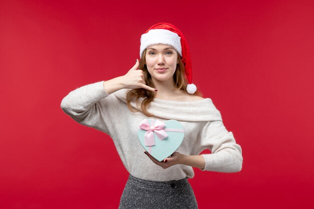 Free photo front view of young female holding present on red