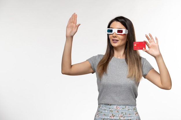 Front view young female holding red bank card in d sunglasses waving her hand on white surface