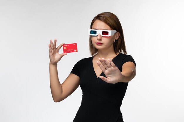 Front view young female holding red bank card in d sunglasses on white surface