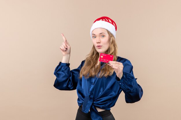 Front view young female holding red bank card on pink background holidays photo new year xmas money emotion
