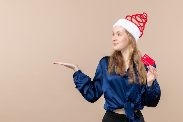 Front view young female holding red bank card on pink background money holiday photo new year xmas emotion free space