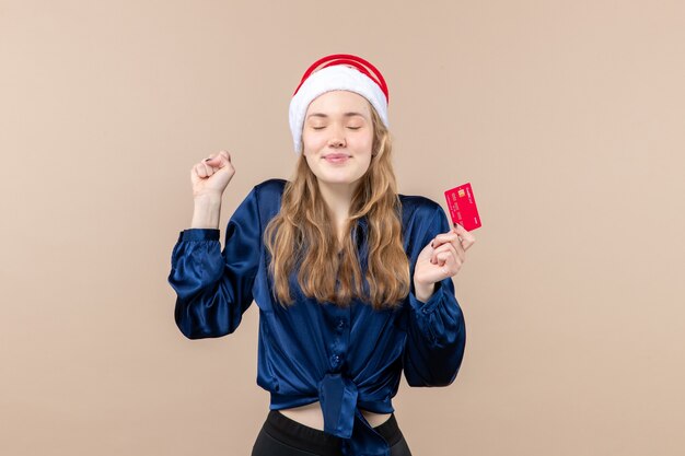 Front view young female holding red bank card on pink background xmas money photo holiday new year emotions
