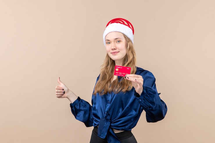 Free Photo front view young female holding red bank card on pink desk holiday photo new year xmas money emotion