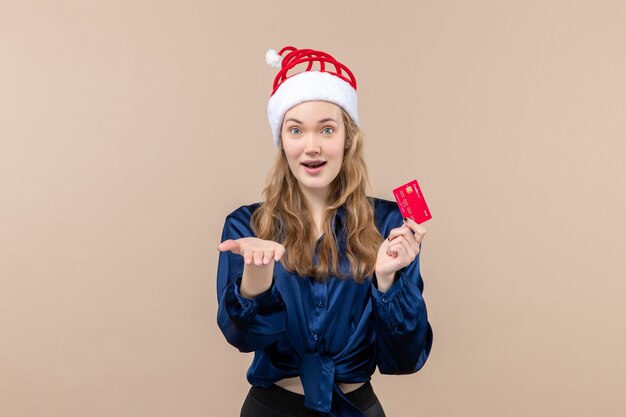 Front view young female holding red bank card on pink desk xmas money photo holiday new year emotion