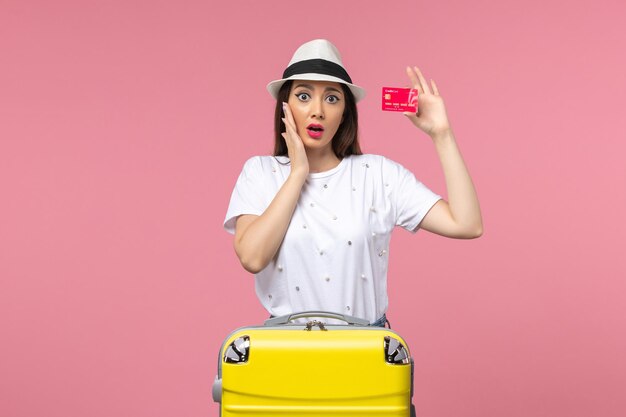 분홍색 벽 색상 여행 여름 항해에 빨간색 은행 카드를 들고 전면 보기 젊은 여성
