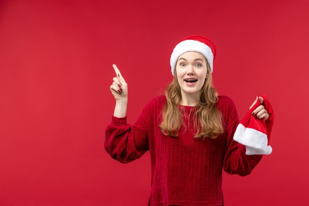 笑顔、休日のクリスマスの赤い帽子を保持している若い女性の正面図