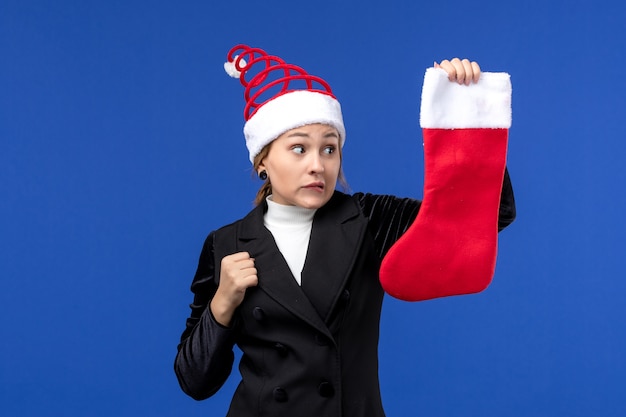 Вид спереди молодая женщина держит красный рождественский носок на синей стене праздник новый год человека