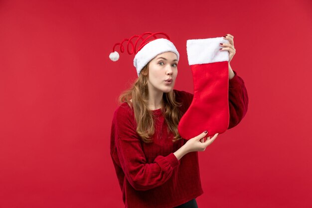 Front view young female holding red christmas sock, holidays red woman