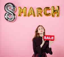 Free photo front view young female holding red sale nameplate on pink marriage party womens day presents shopping holiday