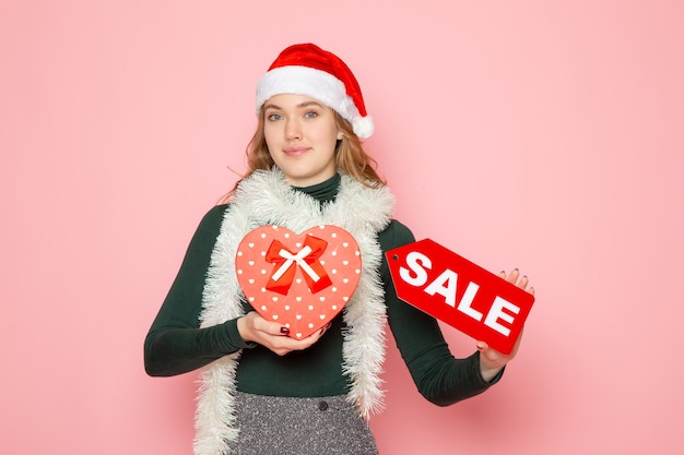 Front view young female holding red sale writing on pink wall new year shopping fashion emotion holiday