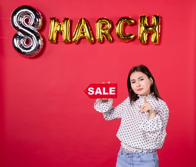 Front view young female holding sale nameplate on march decorated red background equality shopping love affectionate horizontal beauty woman holiday