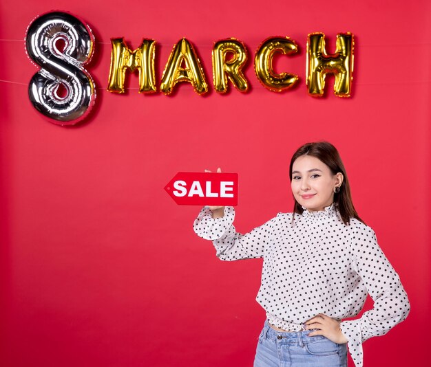 Front view young female holding sale nameplate on march decorated red background passion love affectionate beauty equality woman holiday feminine