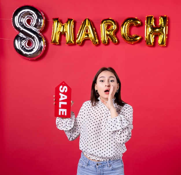 Front view young female holding sale nameplate on march decorated red background passion love affectionate horizontal beauty equality woman feminine