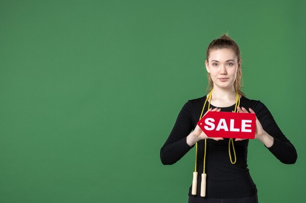 Front view young female holding sale writing on green background body health woman sport gymnastics workout shopping athlete