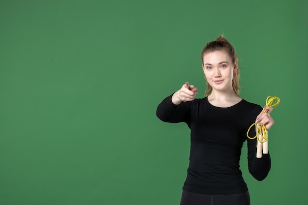 緑の背景に縄跳びを持っている若い女性の正面図女性のトレーニングカラースポーツアスリート体操の健康