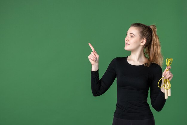 緑の机の上の縄跳びを持っている若い女性の正面図女性のトレーニングカラースポーツアスリート体操健康