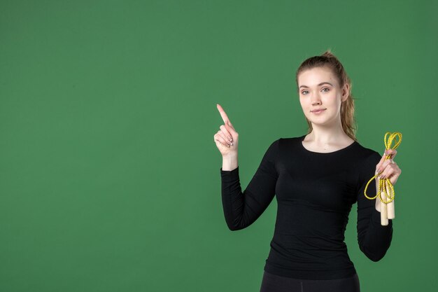 緑の床に縄跳びを持っている若い女性の正面図女性のトレーニングカラースポーツアスリート体操健康