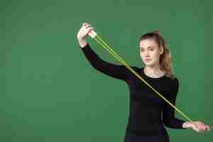 Free photo front view young female holding skipping rope on green