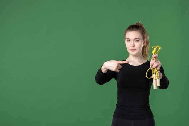 緑の縄跳びを保持している正面図若い女性