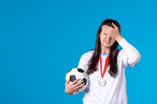 Front view young female holding soccer ball on blue wall