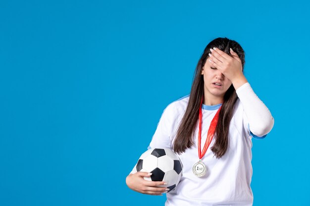 Front view young female holding soccer ball on blue wall