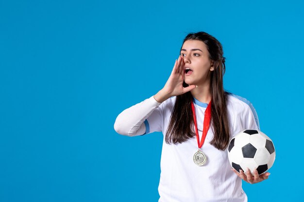 Front view young female holding soccer ball on blue wall