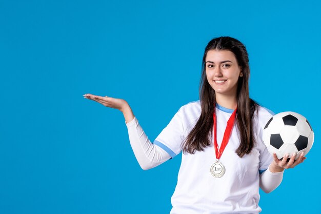 Front view young female holding soccer ball on blue wall