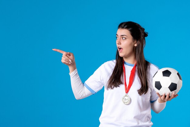 Front view young female holding soccer ball on blue wall