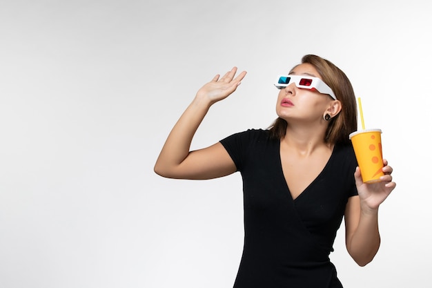 Front view young female holding soda in d sunglasses looking up on white surface