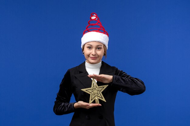 Foto gratuita giocattolo a forma di stella della tenuta della giovane femmina di vista frontale sulla vigilia di capodanno di festa dello scrittorio blu