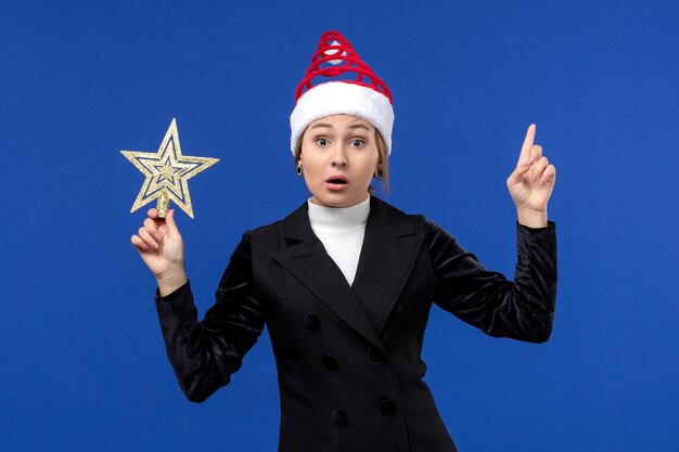 Front view young female holding star shaped toy on a blue desk holiday woman new year