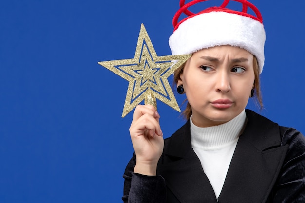 Foto gratuita giocattolo a forma di stella della giovane tenuta femminile di vista frontale sulla vigilia del nuovo anno di feste blu della parete