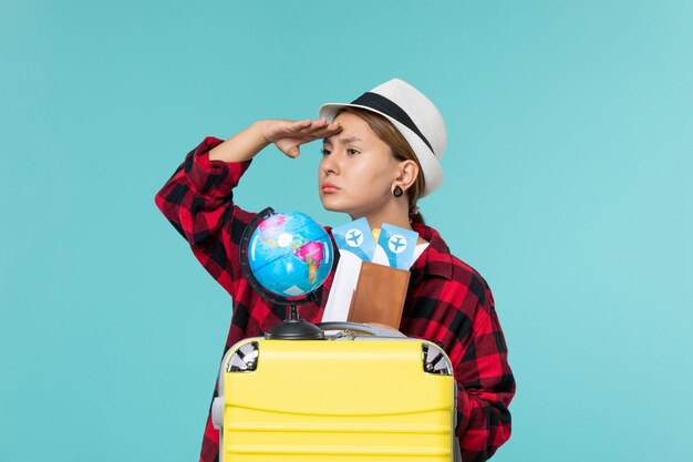 Front view young female holding tickets looking at distance on blue space