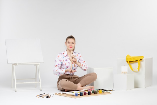 Front view young female holding toy human figure on white background