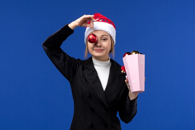 Front view young female holding tree toys on blue background blue emotion new year holidays