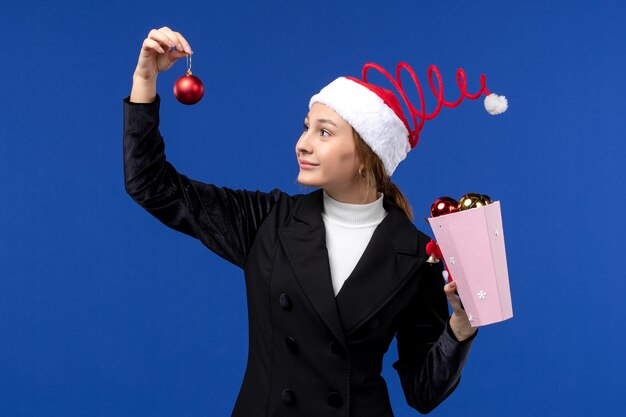 Front view young female holding tree toys on blue background blue emotions new year holidays