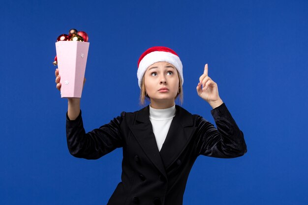 front view young female holding tree toys on blue wall new year holidays woman blue