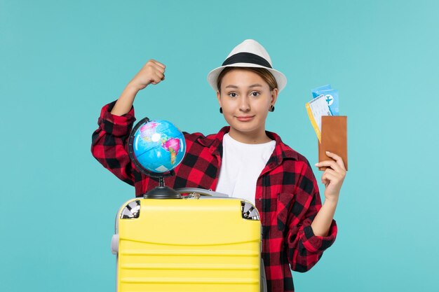 Front view young female holding wallet with tickets smiling on blue space