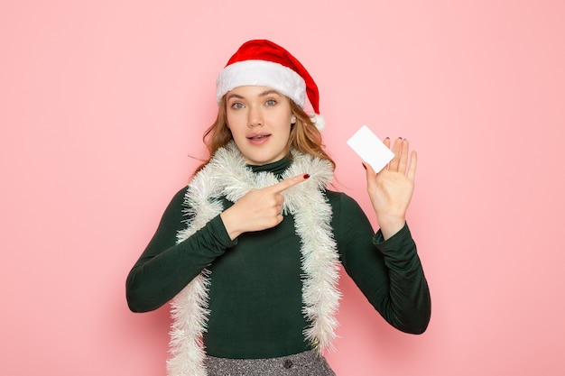 Front view young female holding white bank card on pink wall color emotion model holiday new year