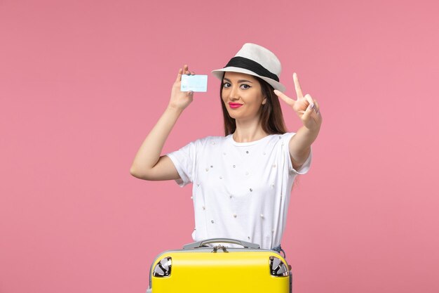 Front view young female holding white bank card on pink wall trip summer emotion woman