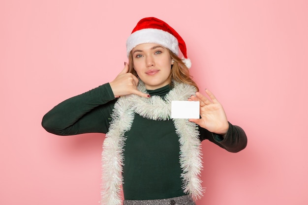 Front view young female holding white bank card smiling on pink wall color emotion model holiday christmas new year