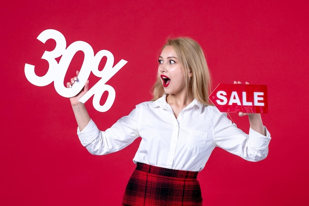 Free photo front view young female holding writing and sale nameplate on red