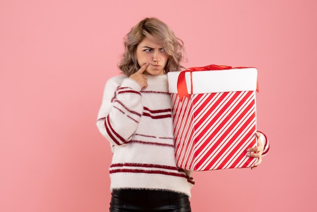 Giovane femmina di vista frontale che tiene regalo di natale con la faccia confusa